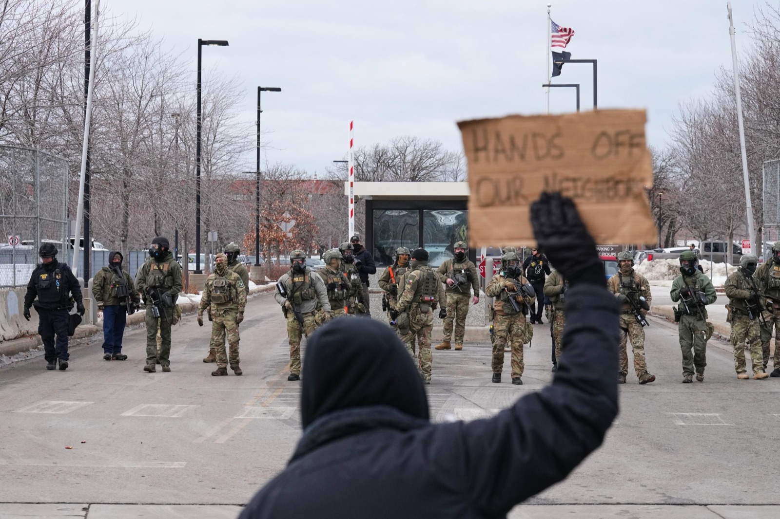 Protester raising a fist toward armed officers blocking a street